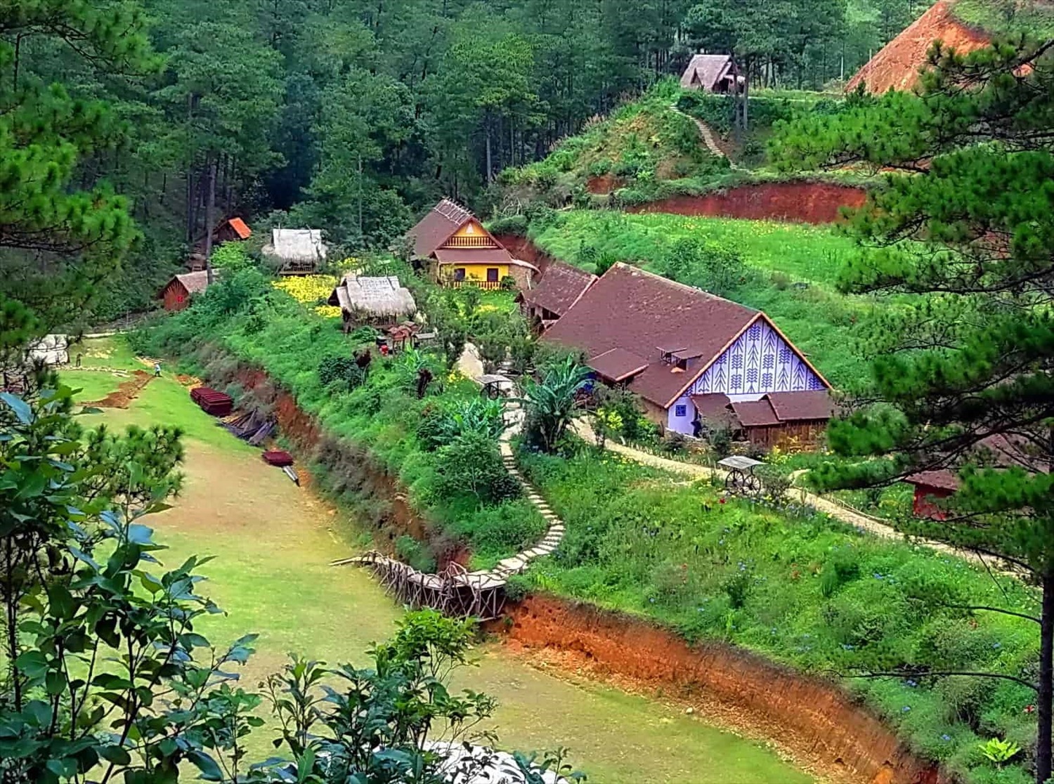 Hình ảnh ngôi làng Cù Lần yên bình giữa rừng núi, nổi bật với những ngôi nhà sàn mộc mạc và khung cảnh thiên nhiên xanh tươi bao quanh.