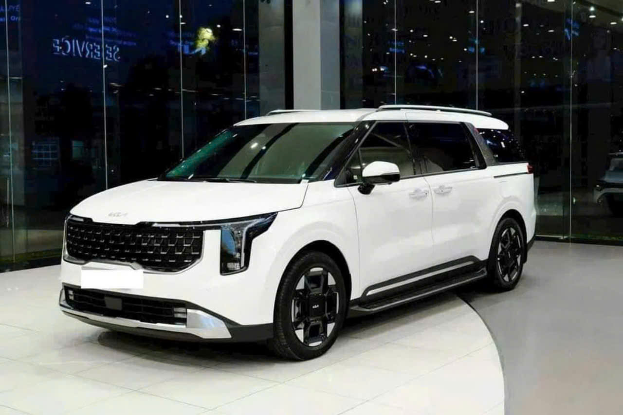 Hình ảnh chiếc Kia Carnival đời mới, màu trắng sang trọng, được trưng bày trong một không gian hiện đại.